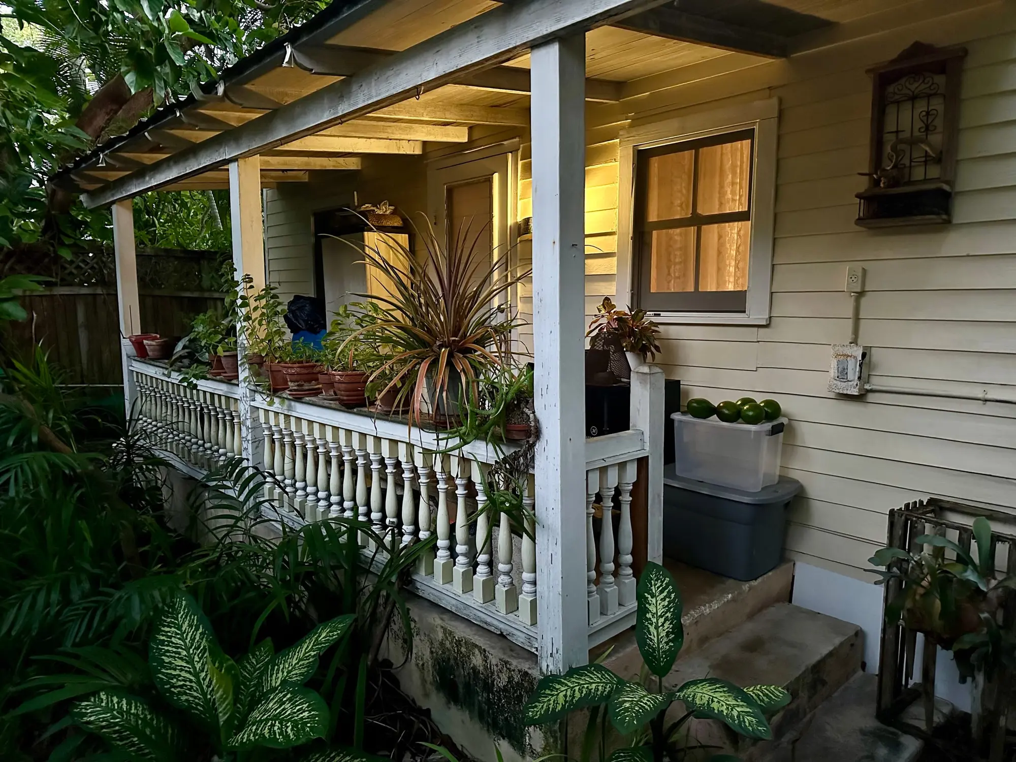 The front porch of a Key West conch house, with a white railing and potted plants