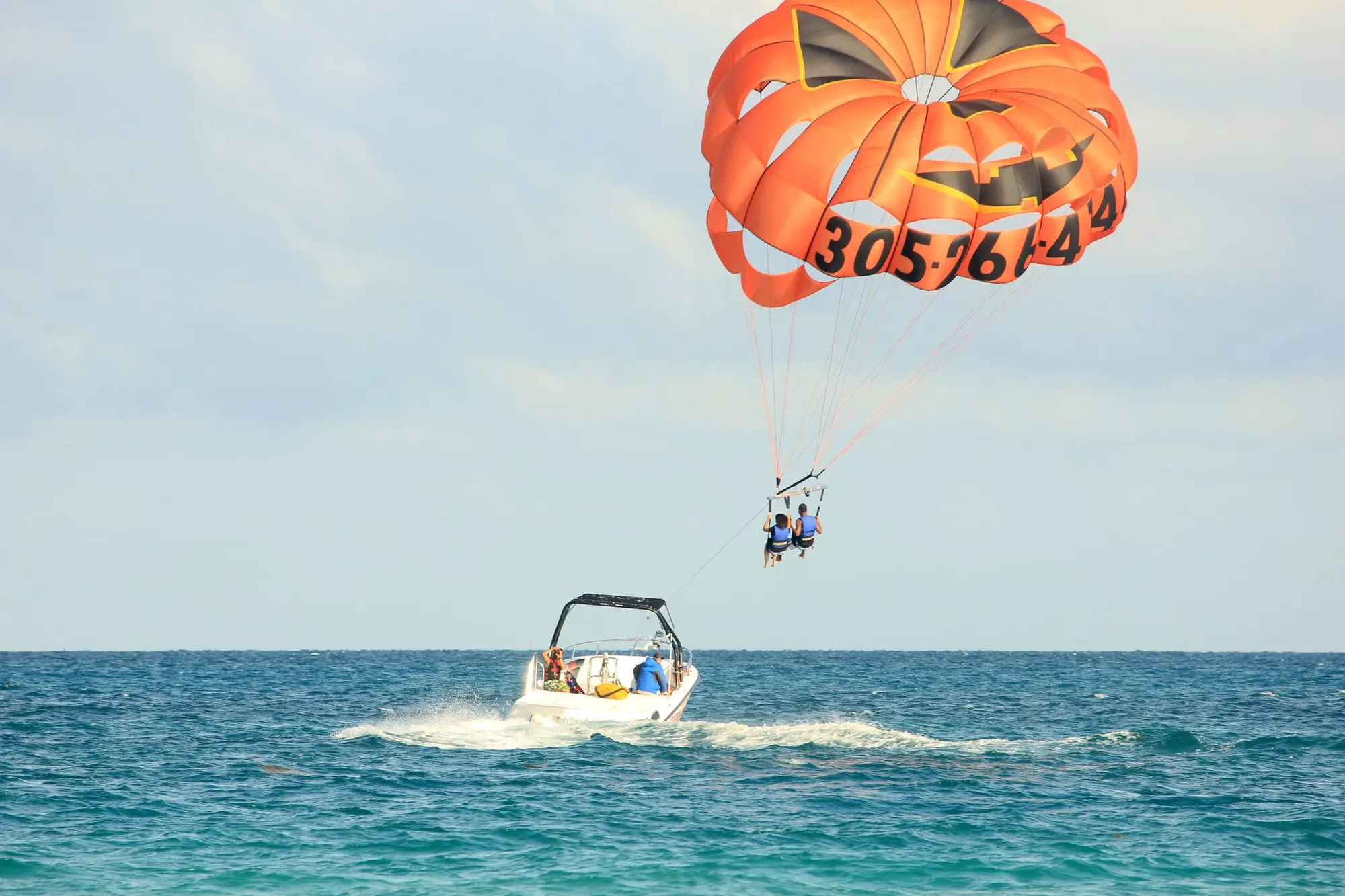 A parasail with two riders towed by a boat off a Florida beach